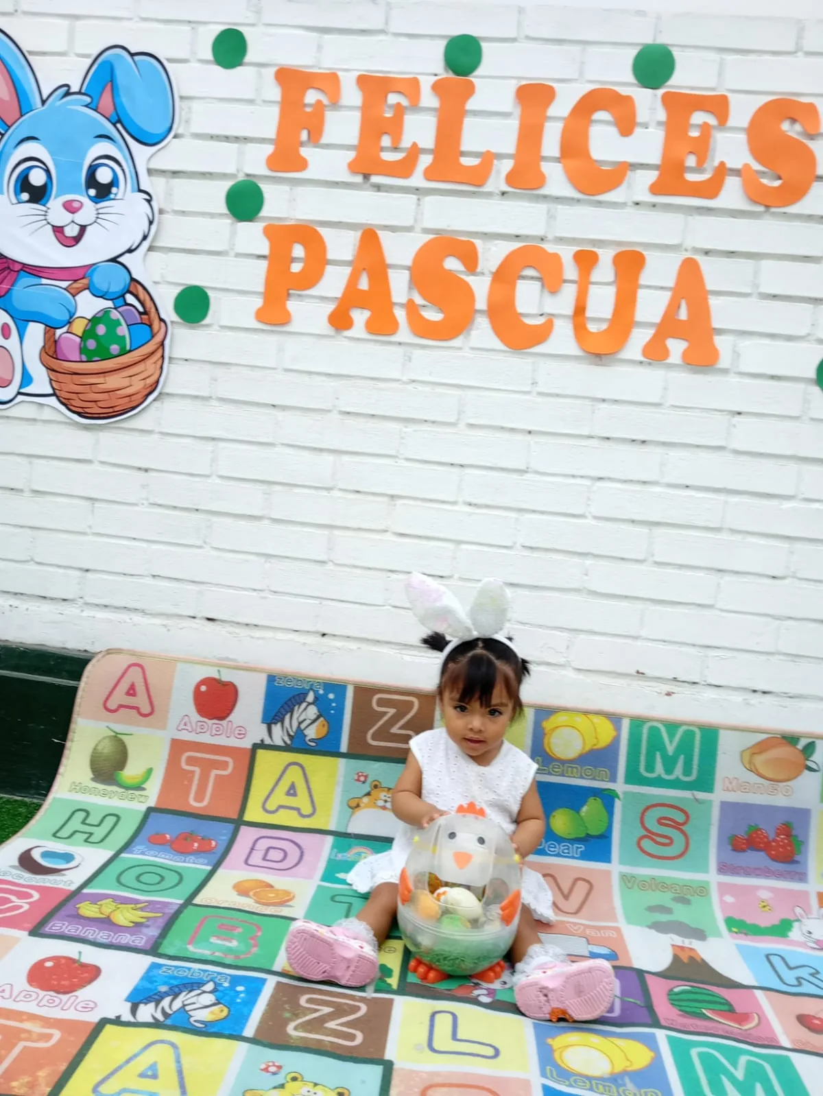 Niña con orejas de conejita frente al cartel Felices Pascua — celebración en guardería Brisa de Hogar
